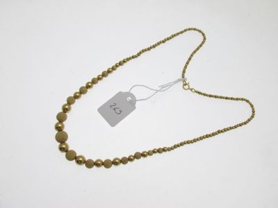 a close up of a gold beaded necklace with a tag on it