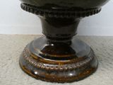 a black vase sitting on a pedestal on the floor
