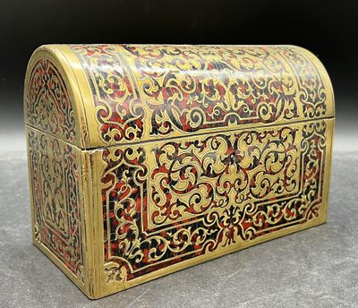 un coffret richement décoré, doré et rouge, posé sur une table