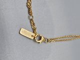 a close up of a gold necklace with a tag on it