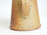 a brown vase with a brown handle on a white surface