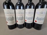 four bottles of red wine are lined up on a table
