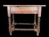 an old wooden table with turned legs on a black background