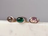 three rings with green and pink stones on a marble surface