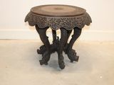 a small table with a carved top on the floor