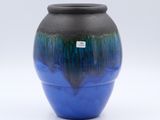 a blue and black vase sitting on a white surface
