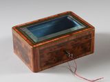 une vieille boîte en bois avec un couvercle en verre, posée sur une surface blanche