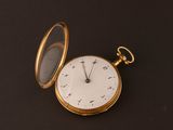 a gold pocket watch sitting on a black surface
