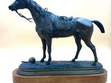 une statue représentant un cheval et un ballon, posée sur un socle en bois