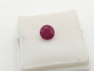 a close up of a red ruby stone on a white surface