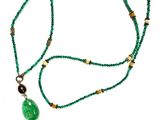 beaded necklace with a green pendant and a tassel on a white background