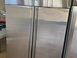 two stainless steel refrigerators stacked on pallets in a warehouse