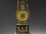 une horloge dorée et verte posée sur un socle, sur une surface grise