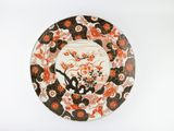 une assiette orange et noire ornée de fleurs sur un fond blanc