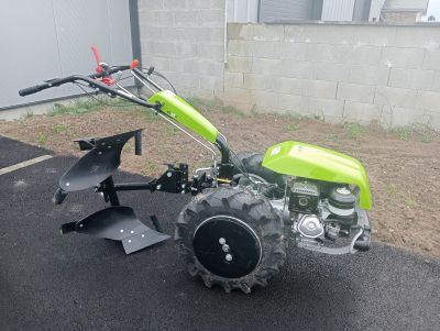 a small green tractor with a plow attached to it