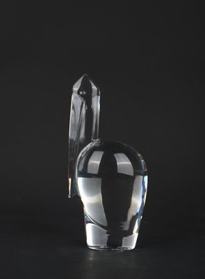 a glass vase with a bird on it on a black surface