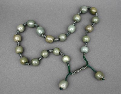 un gros plan d'un collier orné de perles sur un fond gris
