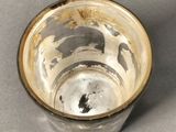a silver cup with a gold rim sitting on a table