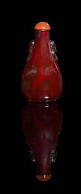 a red vase sitting on a black surface with a black background