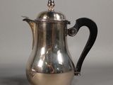 a silver coffee pot with a black handle on a table