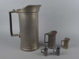 a silver pitcher and two cups next to each other