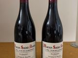 two bottles of red wine sitting on a table next to each other
