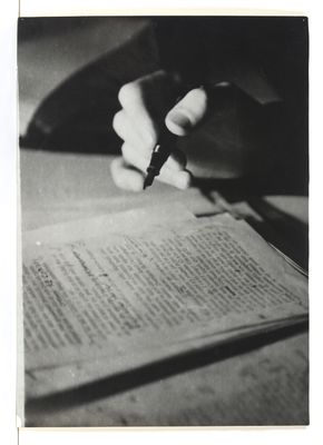 photographie en noir et blanc d'une personne en train d'écrire sur une feuille de papier