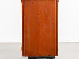 an orange metal box on wheels with a white wall in the background