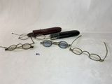 trois paires de lunettes et un stylo posés sur une surface blanche