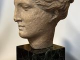 marble bust of a woman with curly hair on a black marble base