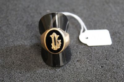 un gros plan d'une bague noire et dorée à laquelle est attachée une étiquette