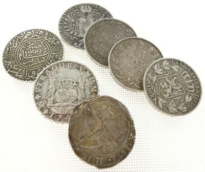 several old coins sitting on top of each other on a white surface