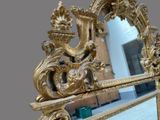 a mirror with a gold frame and a gold decoration on it