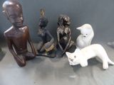 trois figurines représentant des personnes et un chat, posées sur une table