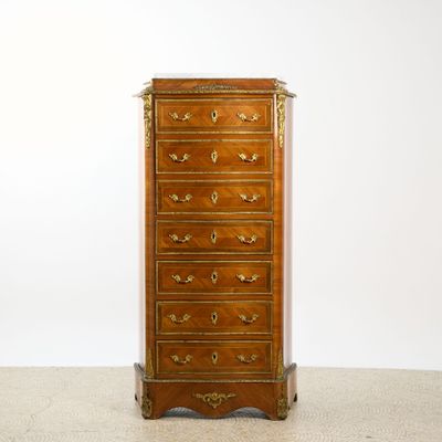 an antique chest of drawers on a carpeted floor in front of a white wall