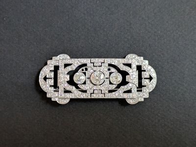 an art deco broochle with diamonds on a black background