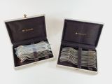 two sets of silverware in a box on a white surface