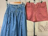 two pairs of skirts hanging on a clothes rack in front of a wall