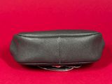 a black leather pencil case sitting on top of a red surface