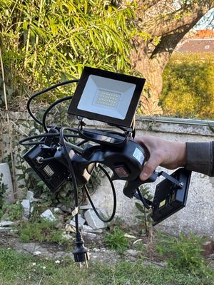 un homme tenant un appareil photo et un ordinateur portable posés sur un trépied