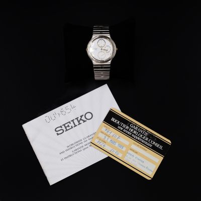 a close up of a watch and a card on a black surface