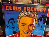 un album d'elvis presley sur une table à côté d'autres disques