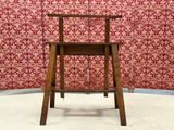 a wooden chair sitting in front of a red wallpapered wall
