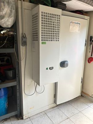 an image of a refrigerator in a garage with a lot of clutter