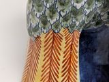 a close up of a vase with a bird on it ' s head