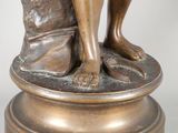 bronze statue of a man holding a book on a pedestal