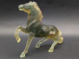 a green glass horse that is standing on its hind legs