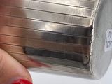 a woman ' s hand holding a metal container with a red nail polish