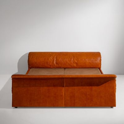 a brown leather couch sitting on a white surface