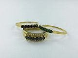 two gold rings with emerald stones on them on a white surface